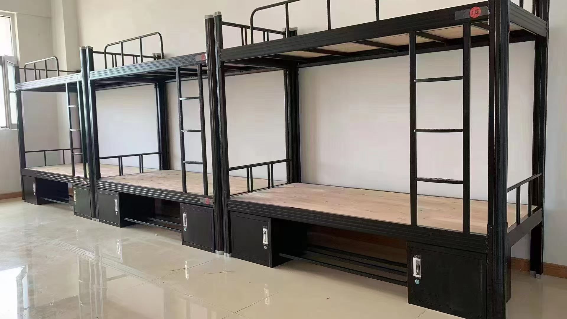 Steel bunk beds for group accommodation Rows of black steel bunk beds with integrated storage for staff accommodation